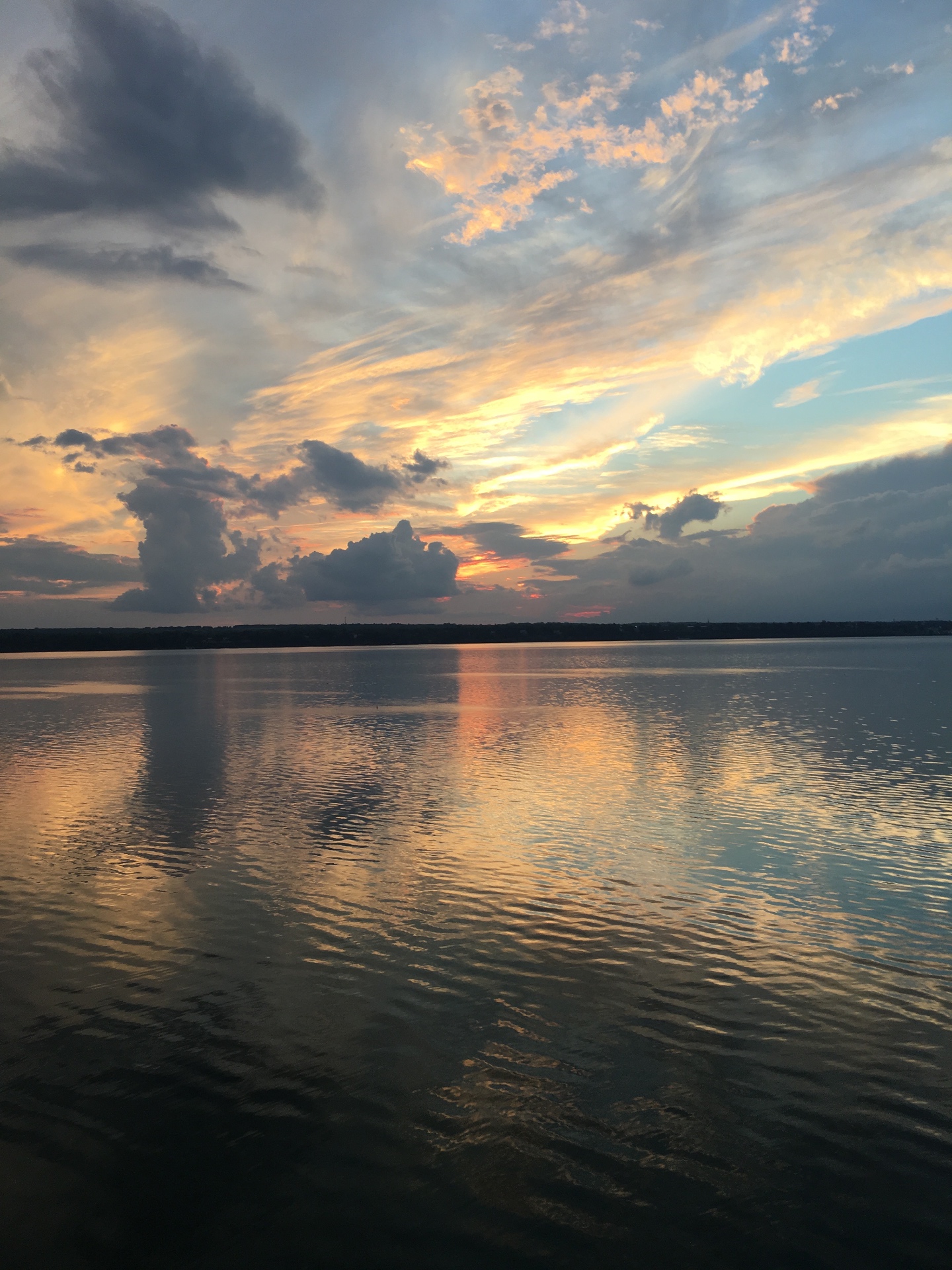 Sunset over a Finger Lake with painted clouds reflected on calm water